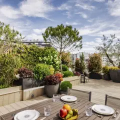 Magnifique aménagement terrasse Paris avec mobilier de jardin, plantes luxuriantes et vue sur la ville.