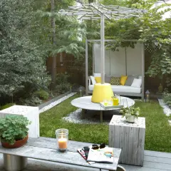 Aménager un petit jardin de 10m2 : un espace détente avec canapé, table basse, bougie et verdure luxuriante.