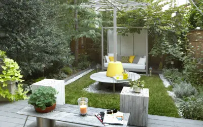 Aménager un petit jardin de 10m2 : un espace détente avec canapé, table basse, bougie et verdure luxuriante.