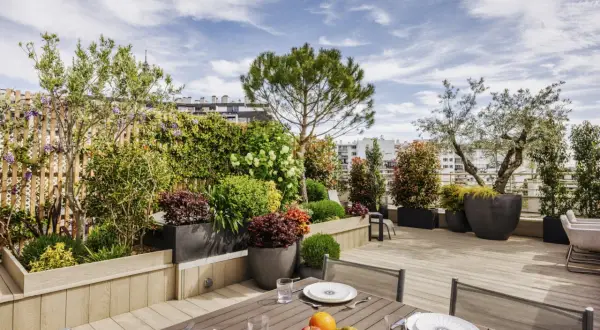 Magnifique aménagement terrasse Paris avec mobilier de jardin, plantes luxuriantes et vue sur la ville.