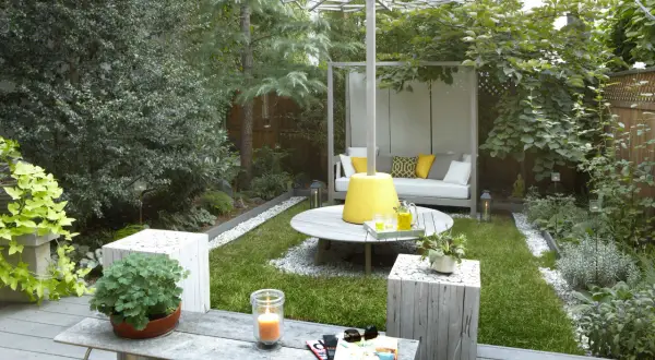 Aménager un petit jardin de 10m2 : un espace détente avec canapé, table basse, bougie et verdure luxuriante.