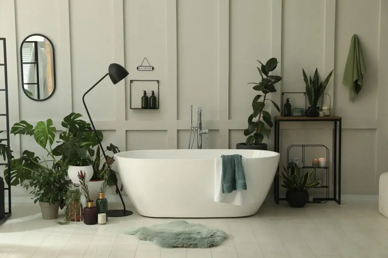 Une salle de bain moderne avec une baignoire blanche, de nombreuses plantes luxuriantes cr&eacute;ant une ambiance de spa.